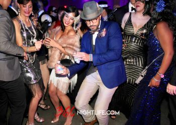 A man in a blue blazer and women in Gatsby themed attire dance at Capital Gatsby New Year's Eve Gala 2022 thrown by 360 Nightlife at HQO in Washington DC.