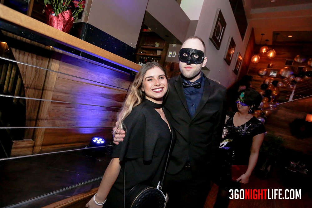 Picture of a man in a black masquerade mask with a woman without a masquerade mask. There is another woman with a masquerade mask that is colorful behind them. This picture was taken at National New Year's Eve Masquerade Ball by 360 Nightlife in Washington, DC. The original website was https://www.360nightlife.com but we have revamped to https://www.360nigthlife.com. Please note: all rights reserved. These photos are sole copyright of 360 Nightlife & should not be used wtihout permission or attribution. 