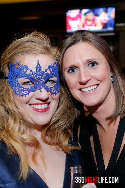Picture of 2 white women. The woman on the left has red hair and is wearing a blue masquerade mask. The woman on the right does not have a mask on but is wearing a black v neck dress. This picture was taken at National New Year's Eve Masquerade Ball by 360 Nightlife in Washington, DC. The original website was https://www.360nightlife.com but we have revamped to https://www.360nigthlife.com. Please note: all rights reserved. These photos are sole copyright of 360 Nightlife & should not be used without permission or attribution. 
