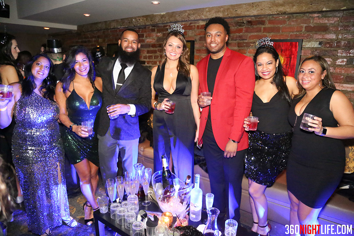 VIP table service at National New Years Eve Masquerade Ball with 360 Nightlife. A large group surrounds the table with bottles of alcohol. It is an African American crowd. Party thrown by 360 Nightlife.